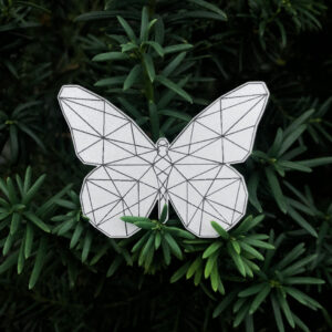 Gray butterfly reflective badge with geometric pattern on a green backround
